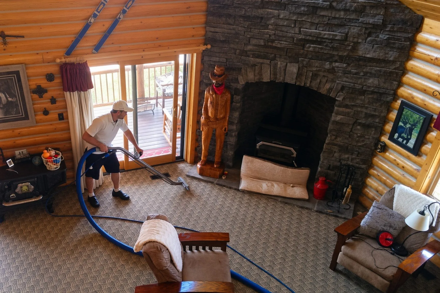 Technician truck-mount extracting carpet in a log home