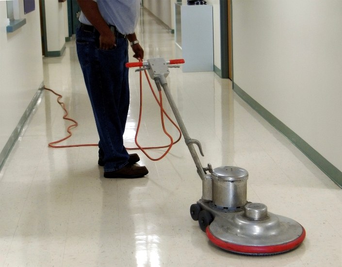 Rotary floor machine on a shiny vinyl tile hallway